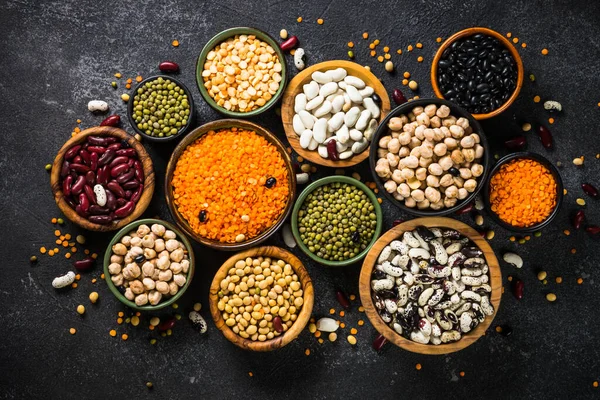 Assortiment de légumineuses, lentilles, pois chiche et haricots sur table en pierre noire. — Photo