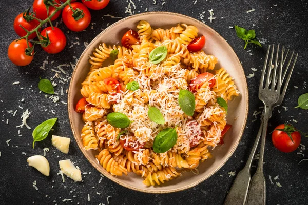 İtalyan makarnası alla arrabiata fesleğen ve parmesan peyniri ile koyu masa.. — Stok fotoğraf