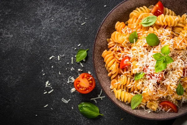 İtalyan makarnası alla arrabiata fesleğen ve parmesan peyniri ile koyu masa.. — Stok fotoğraf