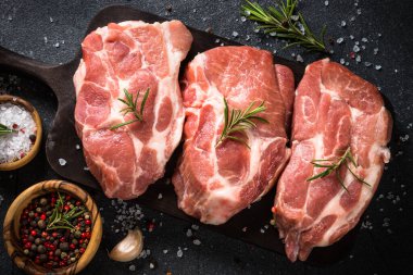 Siyah arka planda baharatlı ve otlu taze biftekler.