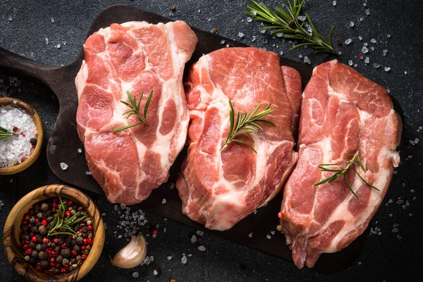 Siyah arka planda baharatlı ve otlu taze biftekler.