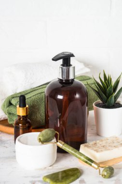 Banyo aksesuarları. Bir şişe sabun, krema, serum ve havlu.