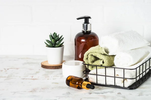 Accesorios de baño. Botella de jabón, crema, suero y toallas — Foto de Stock