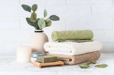 Beyaz banyoda havlular ve kozmetiklerle kaplıca kompozisyonu.