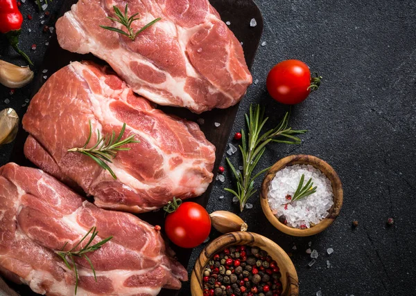 Fresh steaks with herbs and spices at black background. — Stock Photo, Image