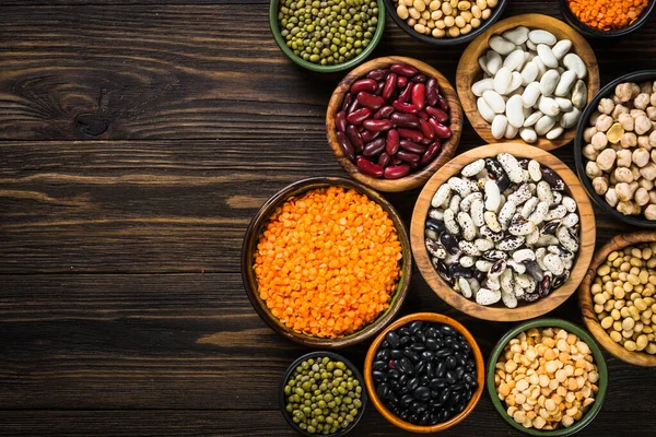 Surtido de legumbres, lentejas, garbanzos y frijoles sobre mesa de piedra negra. — Foto de Stock