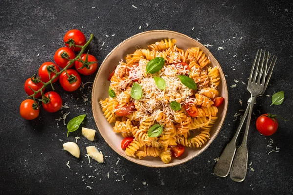 Pasta italiana allá arrabiata con albahaca y queso parmesano sobre mesa oscura. — Foto de Stock