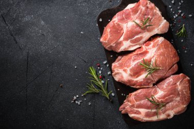 Siyah arka planda baharatlı ve otlu taze biftekler.