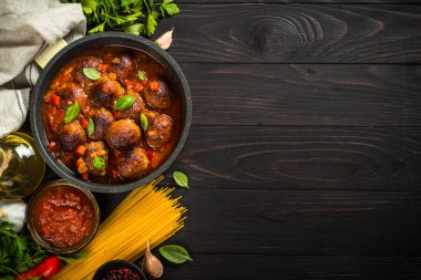 Köfteler domates sosunda ve makarnalar koyu ahşap masada..