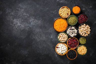 Baklagil, mercimek, bezelye ve fasulye çeşitleri siyah taş masada..