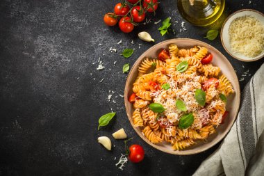 İtalyan makarnası alla arrabiata fesleğen ve parmesan peyniri ile koyu masa..