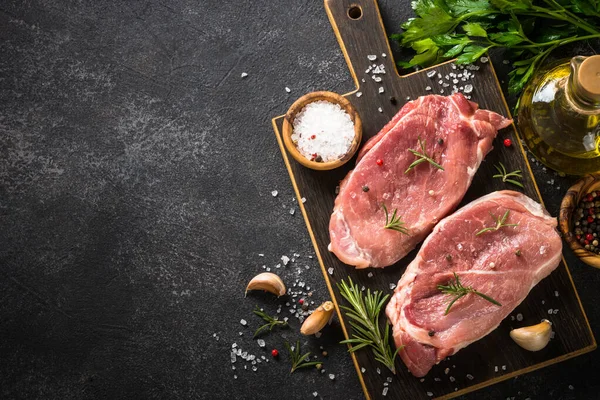 Fresh steaks with herbs and spices at black background. — Stock Photo, Image