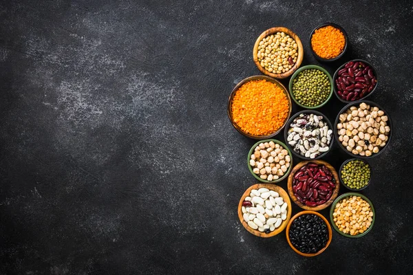 Baklagil, mercimek, bezelye ve fasulye çeşitleri siyah taş masada..