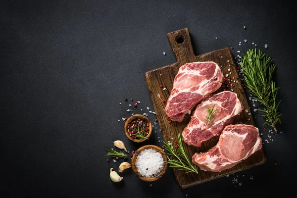 Pork meat at wooden board on black table. — Stock Photo, Image