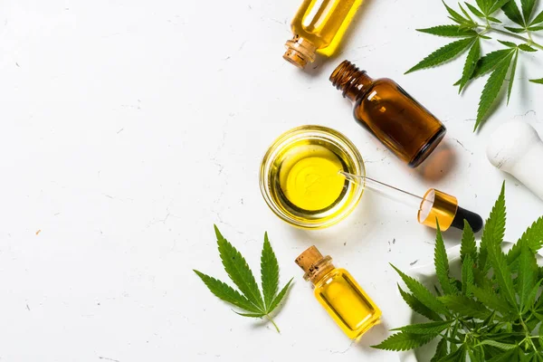 CBD oil in glass bottles and cannabis leaves at white table. — Stock Photo, Image