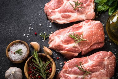 Siyah arka planda baharatlı ve otlu taze biftekler.