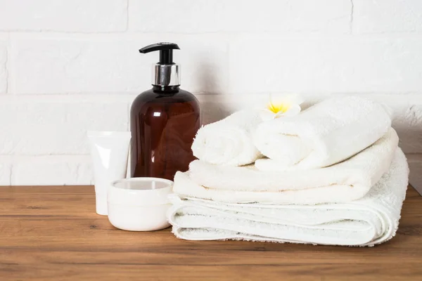 Bottle of soap and stack of towels in white bathroom. — Stock Photo, Image