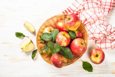Beyaz masadaki sepetin içinde taze kırmızı elmalar.