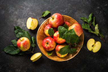 Beyaz masadaki sepetin içinde taze kırmızı elmalar.