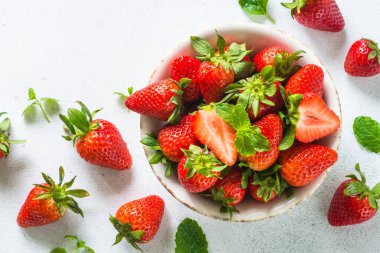 Beyaz masadaki kasede taze olgun çilek.