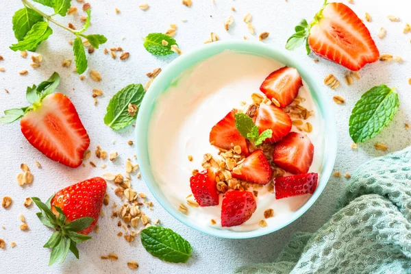 Yogurt with granola and strawberry in white bowl at light stone table. —  Fotos de Stock