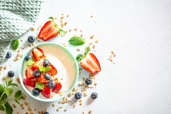 Йогурт з гранолою та свіжими ягодами на легкому кам'яному столі . — стокове фото