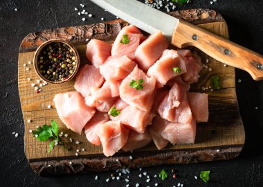 Siyah taş masadaki ahşap tahtada baharatla dilimlenmiş hindi eti.