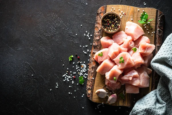 Siyah taş masadaki ahşap tahtada baharatla dilimlenmiş hindi eti.