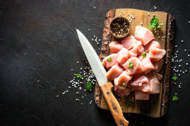 Siyah taş masadaki ahşap tahtada baharatla dilimlenmiş hindi eti.