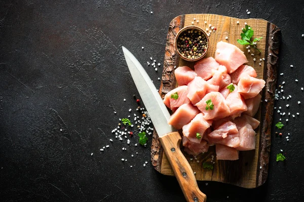 Siyah taş masadaki ahşap tahtada baharatla dilimlenmiş hindi eti.