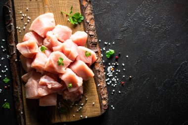 Siyah taş masadaki ahşap tahtada baharatla dilimlenmiş hindi eti.