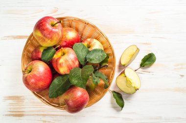 Beyaz masadaki sepetin içinde taze kırmızı elmalar.