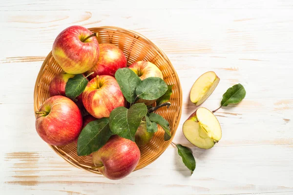 Beyaz masadaki sepetin içinde taze kırmızı elmalar.