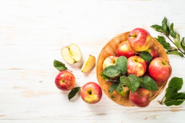 Beyaz masadaki sepetin içinde taze kırmızı elmalar.