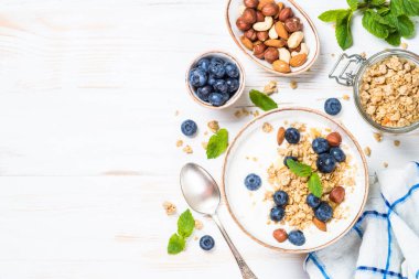 Beyaz ahşap masada taze yaban mersinli yoğurt taneciği..