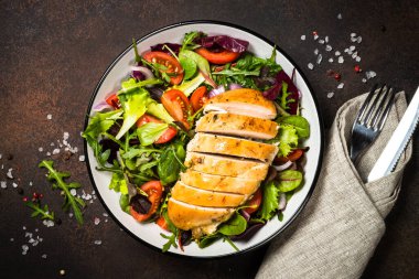 Mutfak masasında fırında tavuk göğsü ve yeşil salata..