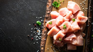 Siyah taş masadaki ahşap tahtada baharatla dilimlenmiş hindi eti.