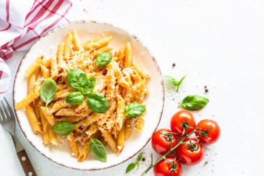 Beyaz masada domates soslu İtalyan makarnası, fesleğen ve parmesan peyniri..