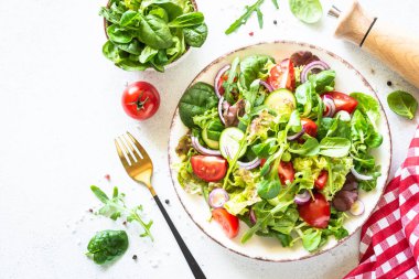 Yeşil salata, taze salata yaprakları ve beyaz tabakta sebzeler..