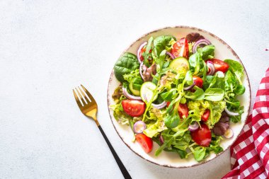 Yeşil salata, taze salata yaprakları ve beyaz tabakta sebzeler..