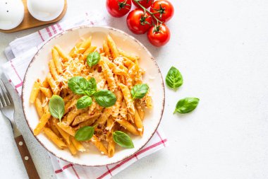 Beyaz masada domates soslu İtalyan makarnası, fesleğen ve parmesan peyniri..