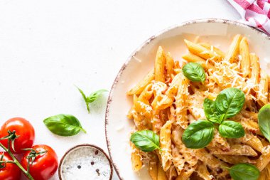 Beyaz masada domates soslu İtalyan makarnası, fesleğen ve parmesan peyniri..