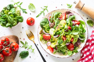 Yeşil salata, taze salata yaprakları ve beyaz tabakta sebzeler..