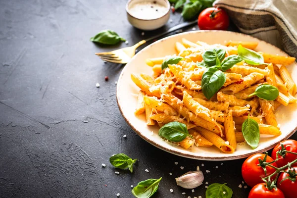 黒テーブルの上にトマトソース、バジル、パルメザンチーズとイタリアのパスタ. — ストック写真
