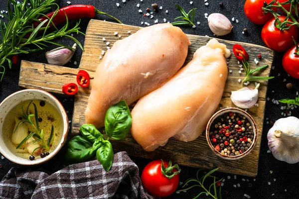 Baharatlı tavuk fileto göğsü ve siyah masada ahşap tahtada sebze..