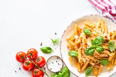 Beyaz masada domates soslu İtalyan makarnası, fesleğen ve parmesan peyniri..