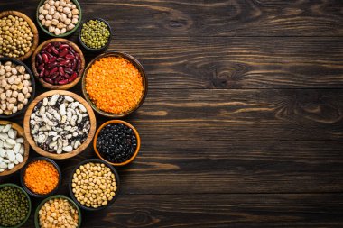 Baklagil, mercimek, bezelye ve fasulye çeşitleri ahşap masadaki farklı kaselerde. Üst Manzara. Vejetaryen yemeği, alt et.