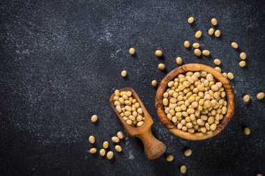 Soya bitkisel protein kaynağıdır. Vejetaryen yemeği. Siyah taş masadaki tahta kasede soya fasulyesi..