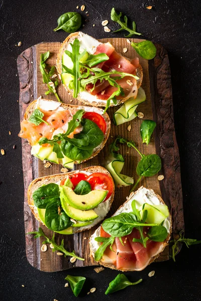 Krem peynirli sandviç seti, prosciutto, somon, avokado ve taze yeşillik. Üst görünüm koyu, dikey biçimdeName.
