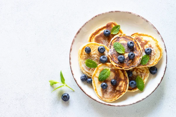 白テーブルで新鮮なブルーベリーと蜂蜜とパンケーキ 健康的な朝食やデザート コピースペース付きのトップビュー — ストック写真
